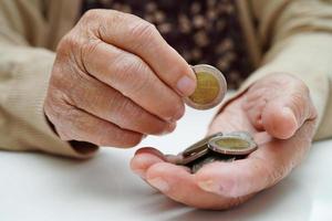 une femme âgée à la retraite comptant des pièces de monnaie et s'inquiète des dépenses mensuelles et du paiement des frais de traitement. photo