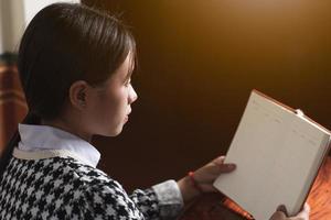 un jeune étudiant lit un livre scolaire pour apprendre et se prépare à l'examen et aux devoirs sur la table, le concept d'éducation et d'étude, l'espace de copie arrière pour le texte individuel photo