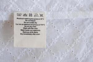 Entretien de la lessive instructions de lavage étiquette de vêtements sur fond de texture de tissu photo