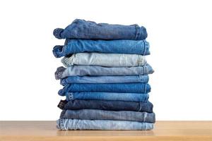 Pile de jeans bleu denim sur table en bois isolé sur fond blanc photo