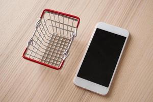 téléphone mobile avec panier sur fond de table en bois shopping concept en ligne photo