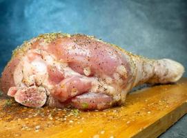 les pilons de dinde aux épices se trouvent sur une planche à découper de cuisine. jambe de dinde. la viande juteuse attend d'être cuite. en attendant le four. jambon photo