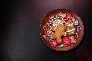 beau pain d'épice sur une plaque en céramique marron avec des décorations d'arbre de noël sur un fond de béton foncé photo