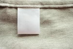 étiquette de vêtements de soin de lessive blanche vierge sur fond de texture de tissu gris photo