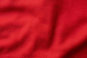 maillot de football de vêtements de sport en tissu rouge avec fond de texture en maille d'air photo