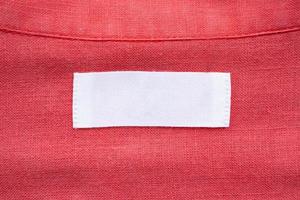 Étiquette d'étiquette de vêtements blanc vierge sur fond de texture de tissu de chemise en lin rouge photo