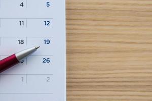 page de calendrier sur fond de table en bois avec pointe de stylo à la 19e date photo