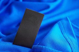 Étiquette de vêtements de soin de lessive vierge noire sur fond de chemise de sport en polyester jersey bleu photo