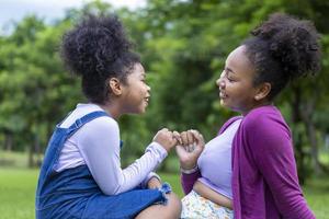 une mère afro-américaine fait une promesse rose à sa jeune fille tout en faisant un pique-nique d'été dans le parc public pour le concept d'amour et de bonheur photo