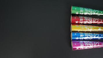 cornes de soufflage en papier en rouge, vert, or, bleu, violet pour le nouvel an et la fête de noël sur fond noir.pas de personnes photo