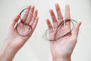 une femme asiatique a un problème avec la perte de cheveux longs attachée dans sa main. photo