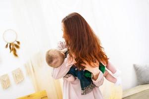 belle jeune femme tient une petite fille dans les mains. portrait de famille de la mère et de la fille. photo