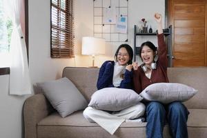 deux jeunes femmes applaudissent ensemble pour le sport à la télévision dans un salon confortable à la maison. photo