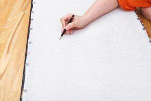 L'artiste dessine un motif au crayon sur soie photo