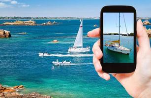 touriste prenant une photo de yacht près de la bretagne