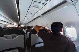 l'homme regarde dans la fenêtre de l'avion. nouvelle cabine d'avion avec des sièges confortables. vol en classe économique de la nouvelle compagnie aérienne sans retard de vol. photo