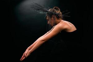 portrait d'une belle jeune femme comme une sorcière avec des lèvres rouges et une couronne noire sur fond sombre. beauté noire noire, concept d'halloween photo