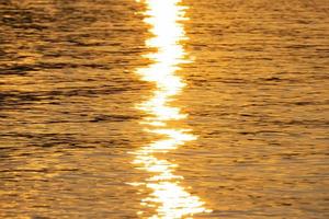gros plan de la mer, texture dorée du coucher de soleil sur l'eau photo