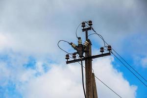 lignes électriques de poteau électrique fils électriques sortants contre le ciel bleu nuageux. photo