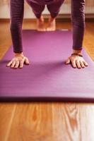 jambes et mains d'une femme sur un tapis de yoga pratiquant des asanas photo