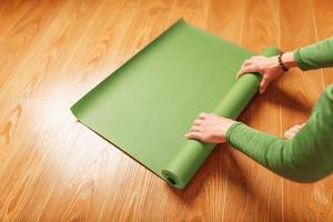 une femme déroule un tapis vert avant un cours de yoga photo