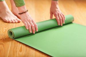 une femme déroule un tapis vert avant un cours de yoga photo