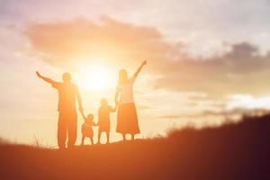 famille heureuse dansant sur la route au coucher du soleil. soirée sur la nature photo