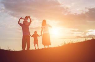 famille heureuse dansant sur la route au coucher du soleil. soirée sur la nature photo