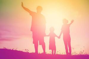 silhouette d'une famille heureuse et d'un coucher de soleil heureux photo