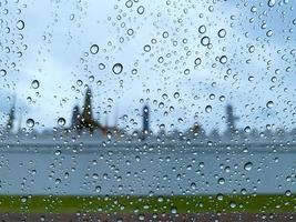 goutte d'eau sur la vitre de la voiture lorsqu'il pleut pendant la saison de la mousson avec un arrière-plan flou. photo