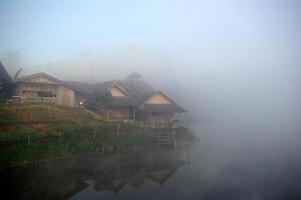 maison en bois dans la brume matinale et vue sur le lac à la campagne photo