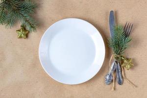 cadre de table de vacances avec branche d'arbre de noël, assiette vide et décorations. concept de nourriture à plat du nouvel an photo