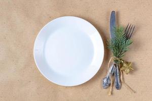 cadre de table de vacances avec branche d'arbre de noël, assiette vide et décorations. concept de nourriture à plat du nouvel an photo