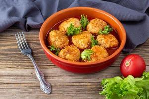 boulettes de viande à la sauce tomate dans un bol sur une table en bois. photo