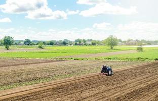 un tracteur roule sur un champ agricole. ameublir la surface, cultiver la terre pour de nouvelles plantations. l'élevage et l'agriculture. un agriculteur sur un tracteur avec une fraiseuse desserre, broie et mélange le sol. photo