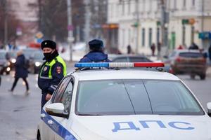 tula, russie 23 janvier 2021 policiers russes de la route debout près de la voiture de patrouille sur la route d'hiver - gros plan avec mise au point sélective sur la lampe de toit. photo