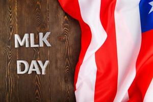 le mot mlk day posé avec des lettres en métal argenté sur une surface en bois avec un drapeau américain froissé sur le côté droit photo