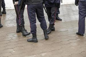 jambes de policiers russes en bottines noires, pantalons à rayures rouges et avec des bâtons de nuit en caoutchouc tonfa. photo