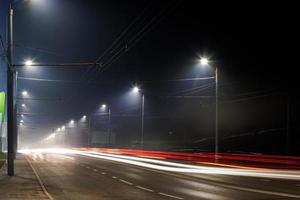 route de nuit brumeuse vide avec des rangées de lampadaires photo