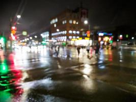 vue sur la rue de la ville de pluie nocturne défocalisée avec des voitures traversant la route photo