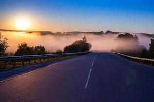 Dence brouillard tôt le matin dans le monde à l'autoroute d'été près de la rivière avec garde-corps photo