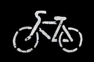 Signe de vélo sur l'asphalte avec de la vieille peinture blanche - isolé sur fond noir photo