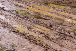 route de boue d'argile sale avec des flaques d'eau et des traces de pneus - gros plan avec mise au point sélective, composition diagonale photo