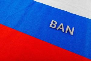 le mot interdiction posé avec des lettres en métal argenté sur le tissu du drapeau de la fédération de russie photo