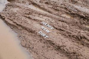 les mots happy new dirt posés avec des lettres en métal argenté sur la surface de la boue humide photo