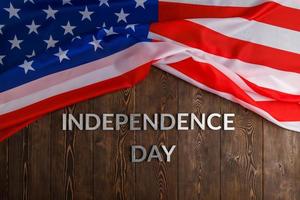 les mots fête de l'indépendance posés sur la surface de planches de bois marron avec le drapeau des états-unis d'amérique froissé photo