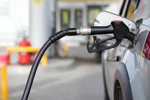 ravitaillement en carburant de voiture de couleur argentée à la station-service de nuit - gros plan avec mise au point sélective et arrière-plan flou photo