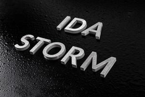les mots ida storm posés avec des lettres en métal argenté sur une surface noire à la fois recouvertes de gouttes d'eau de pluie photo