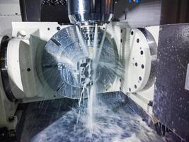 Fraiseuse cnc 5 axes au travail avec liquide de refroidissement sous pression et flou de mouvement des flux.. photo