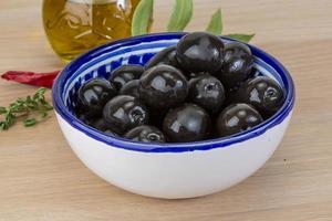 olives noires dans un bol sur fond de bois photo